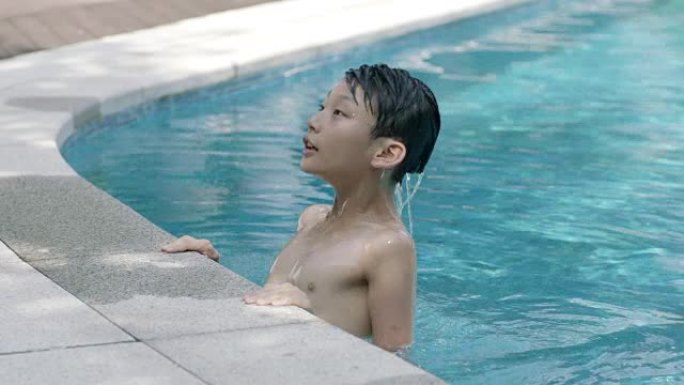 亚洲男孩从游泳池抬起头的特写慢动作