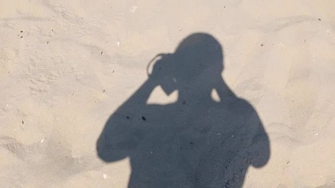 男人走在沙滩上，脱下他的影子