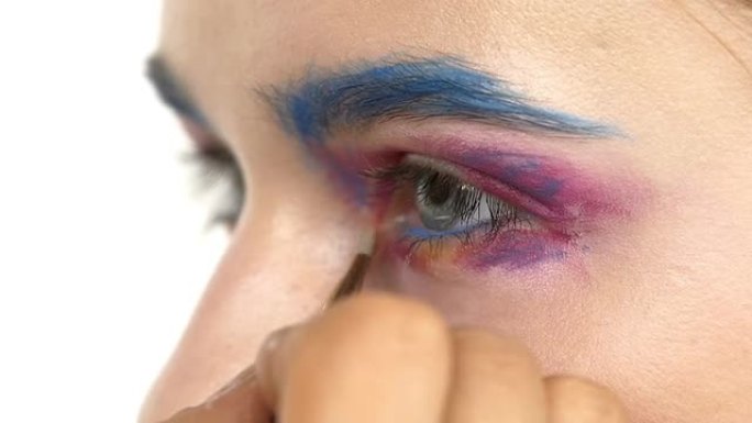 眼部化妆的女人涂抹眼影，制作异国情调，一个，蓝色眉毛，阴影，睫毛膏，画龙点睛，特写，白色，慢动作