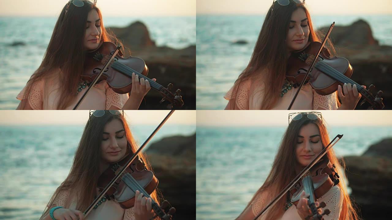 穿着牛仔裤的年轻美丽的高加索女人拉小提琴呆在美丽的大海或海洋附近的海滩上，慢动作