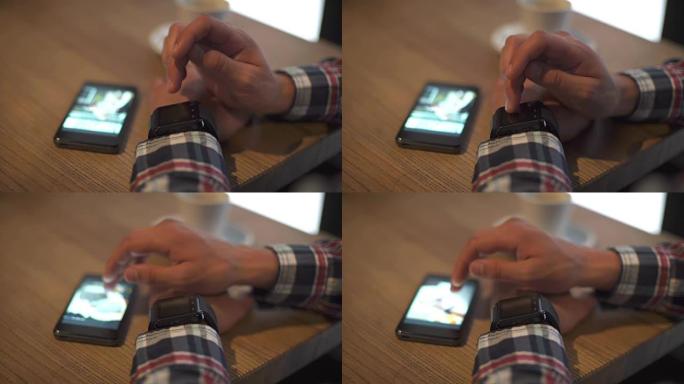 在咖啡馆中使用智能手表和电话的男人的特写镜头