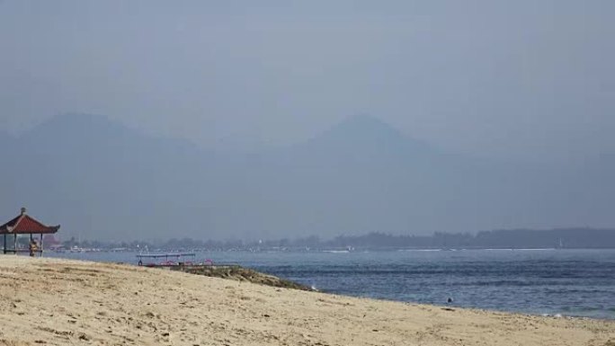 温暖的海浪在热带度假胜地的沙滩上奔跑，带有雨伞和躺椅