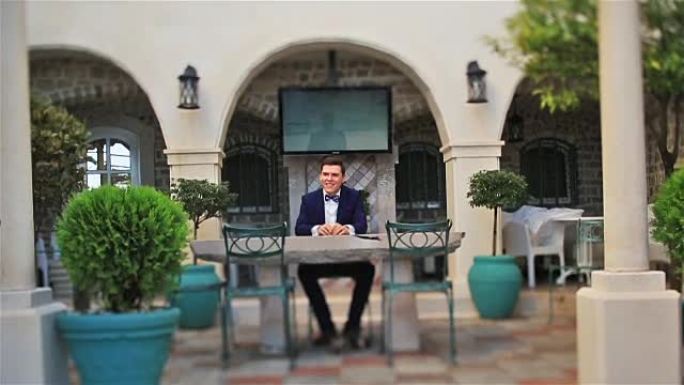 英俊的新郎坐在布德瓦黑山的户外咖啡馆里