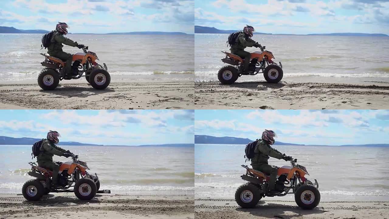 穿过四边形，去海滩。一个在ATV上的人，表演技巧，并以极端的方式驾驶。运动员戴着摩托车戴着头盔。河岸