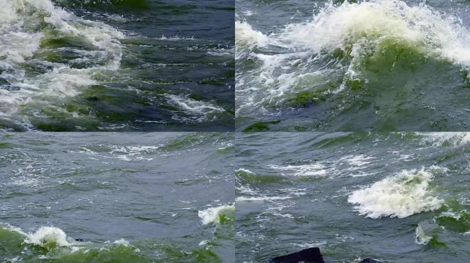 慢动作: 强烈的波浪在石头上滚动。海浪猛烈撞击岩石。喷雾向不同的方向飞行。冷风在吹。海上多云的秋日