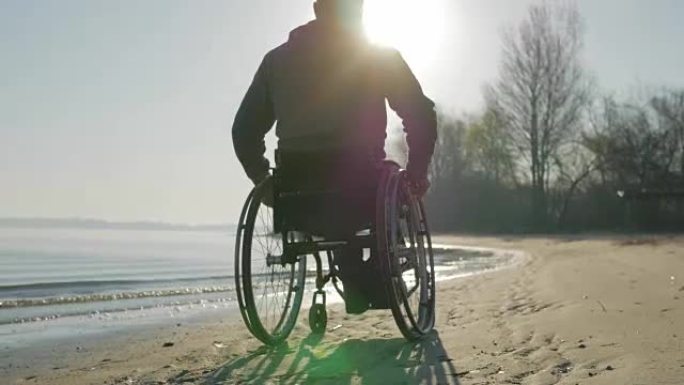 坐在轮椅上的残疾人沿着海滩推着自己