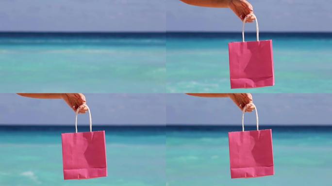 粉色购物袋女性手对抗绿松石加勒比海