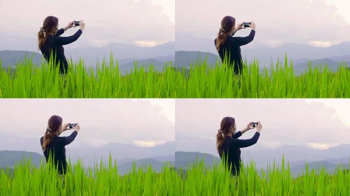 美丽的女人在泰国北部的稻田用智能手机拍照