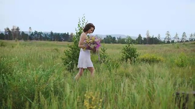 美丽的受启发的女人在一束野花盛开的田野上说话