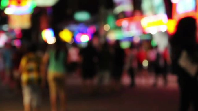 迷离的人群在夜晚的步行街上行走，彩虹灯