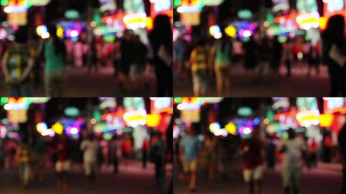 迷离的人群在夜晚的步行街上行走，彩虹灯