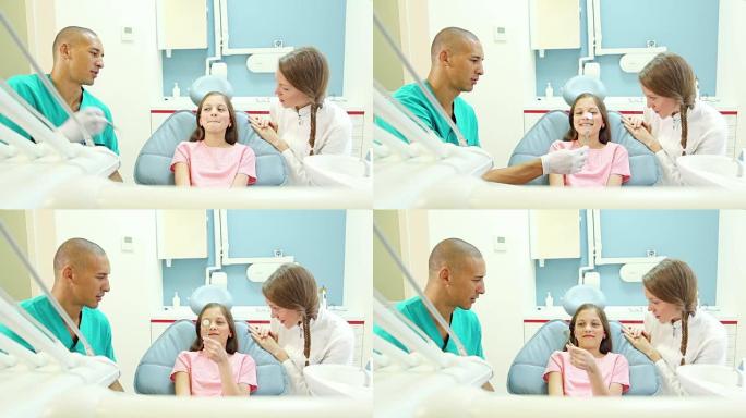 友好的牙科医生和牙医向可爱的小女孩展示口腔镜