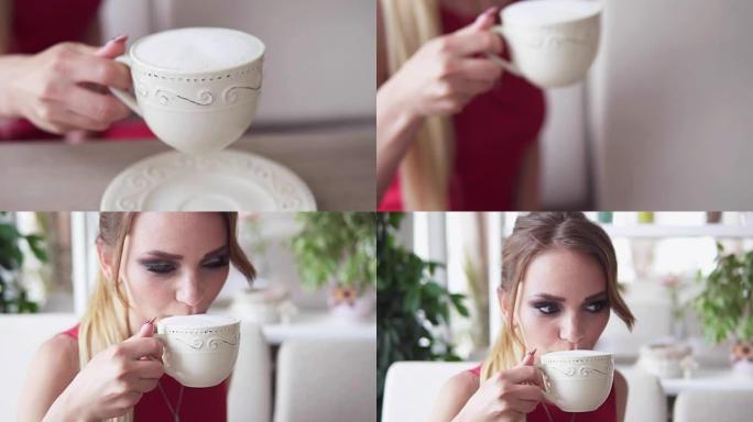 将焦点从带有卡布奇诺咖啡的漂亮白色杯子转移到坐在餐桌旁，在咖啡馆放松并喝咖啡的金发碧眼的年轻女子。慢