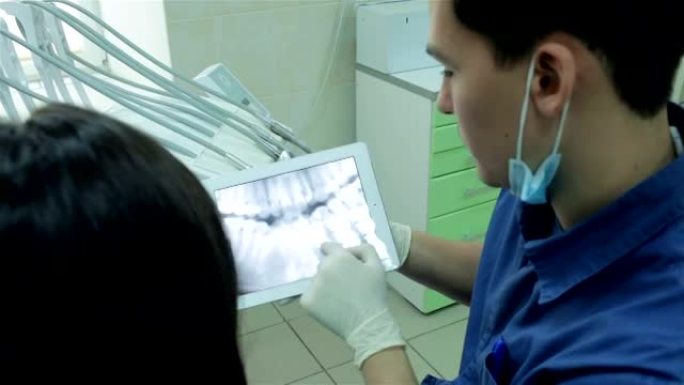 牙医在平板电脑上显示了患者的x射线，并告诉她的牙齿咬合矫正方法