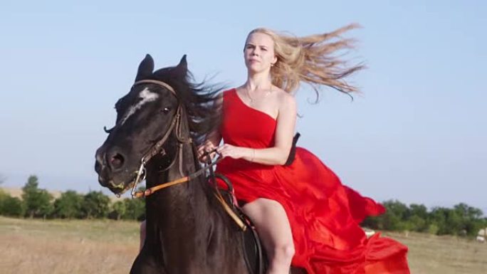 年轻的金发女孩穿着猩红色长礼服骑着黑马