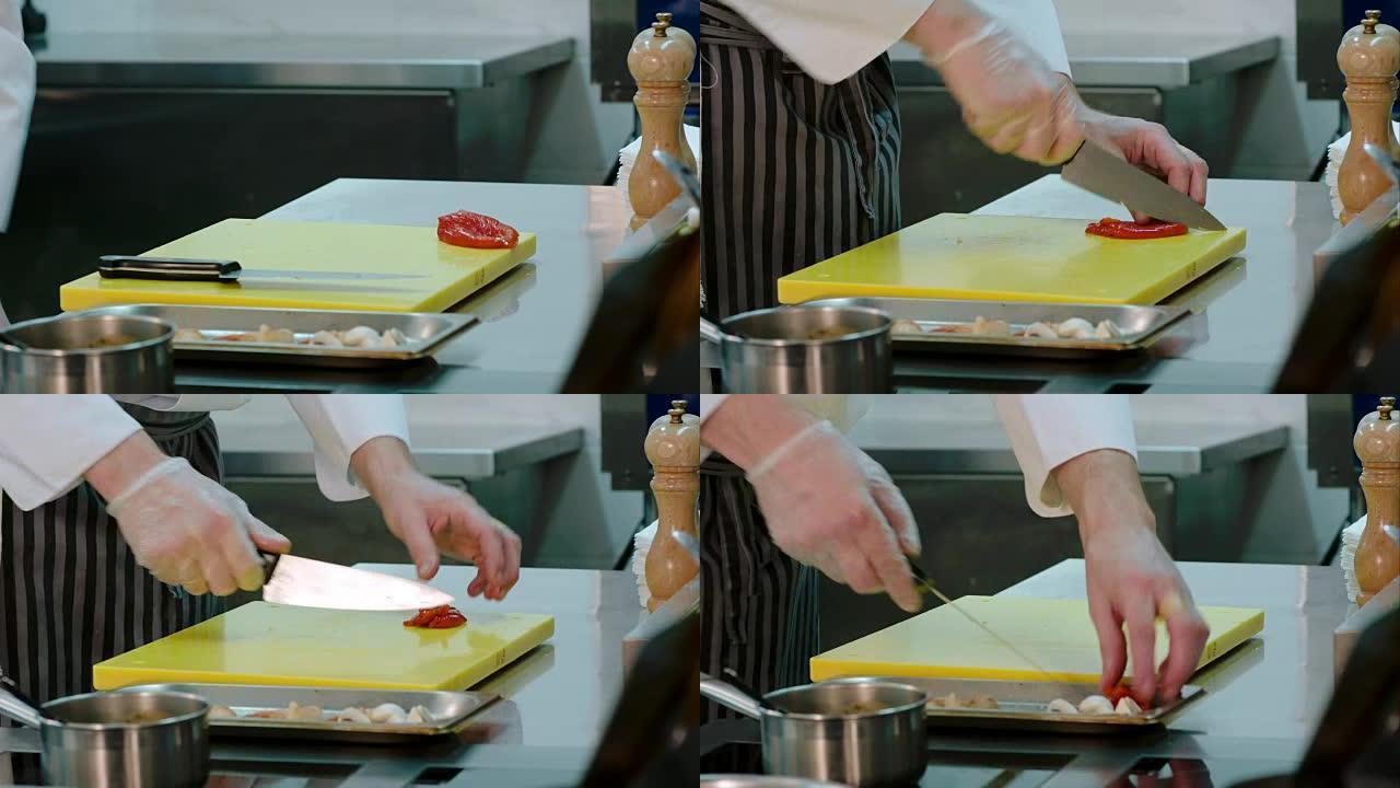 厨师的手将腌制的红甜椒切成薄片，并将其与其他食材放在一起