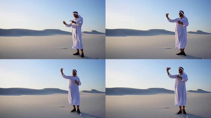 兴高采烈的阿拉伯男游客打电话给朋友的手机视频通话，显示白沙沙漠的环境在炎热的一天