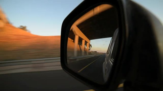 开车通过美丽和稀疏的南部非洲风景在日落，从车内拍摄，看着反射在侧视镜