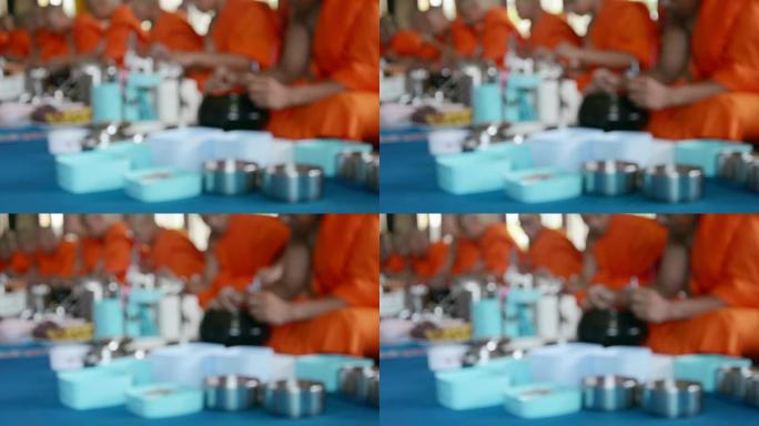在泰国寺庙的传统宗教仪式中，僧侣在吃食物和饮料的运动模糊。