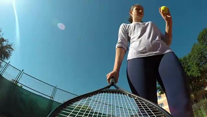 女子手握网球拍在网球场发球的视点