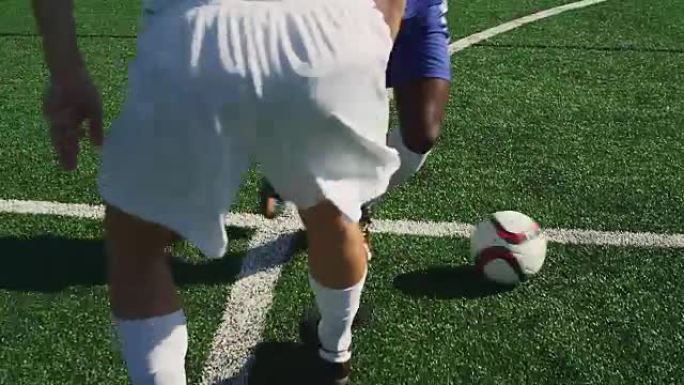 一名足球运动员在球场上运球，对手为他严密辩护。