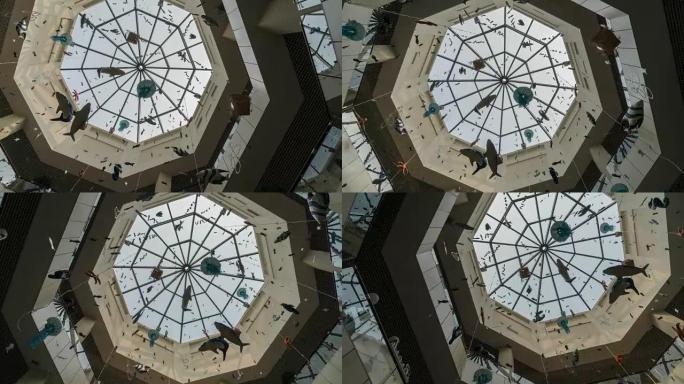 在蓝色的天空上，用纸花环拍摄购物中心玻璃天花板的照片，背景是太阳光线的延时光线