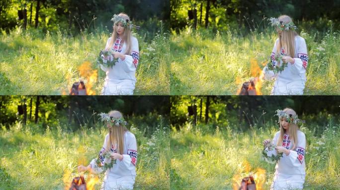 年轻美丽的少女穿着民族装饰刺绣的衬衫，坐在火炉旁的草地上，编了一个花环占卜