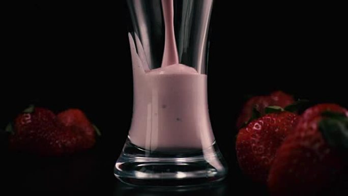 在装有草莓的玻璃杯中倒入奶昔。慢mo