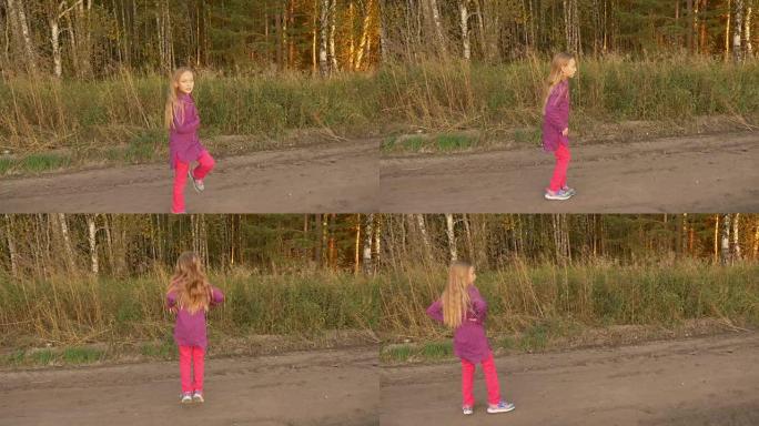 快乐的小女孩在户外跳舞。在晴朗的傍晚，啦啦队在农场路上训练。手持。