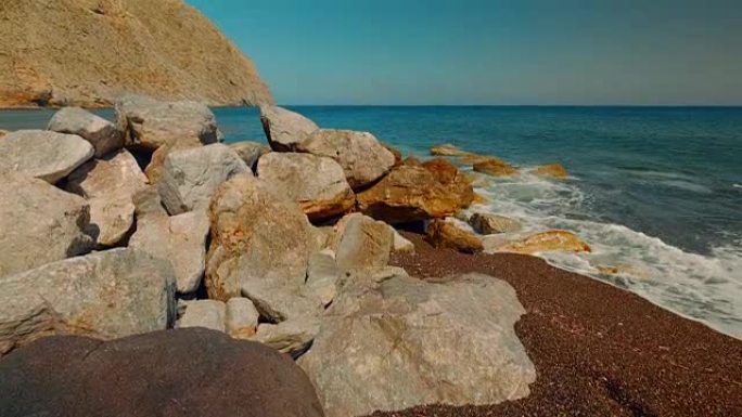 地中海火山海滩的倾斜镜头，红沙和海浪击中岩石