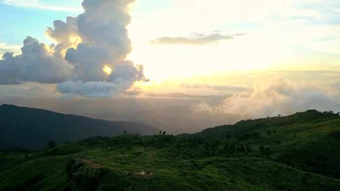 在泰国Chaingrai省的Phu Chi Fa，太阳落在山上蓬松的云的运动后面，黄色的暮光天空