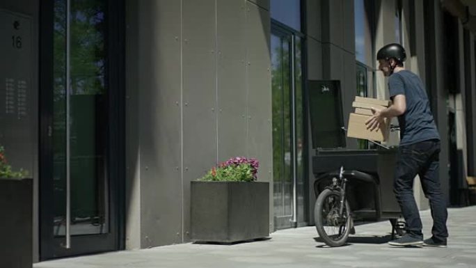 英俊的自行车快递员卸下了他的货运自行车