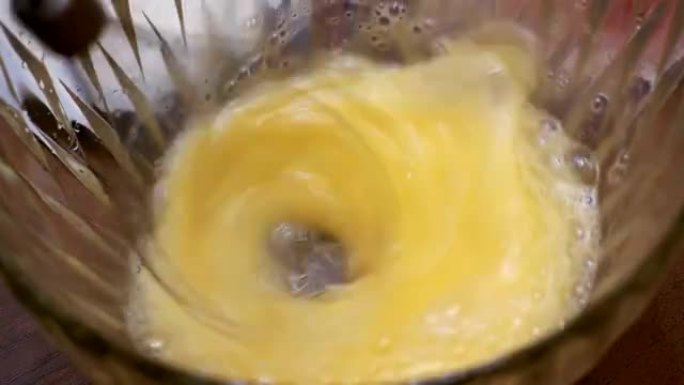 用电动手动搅拌器在透明碗中搅打鸡蛋