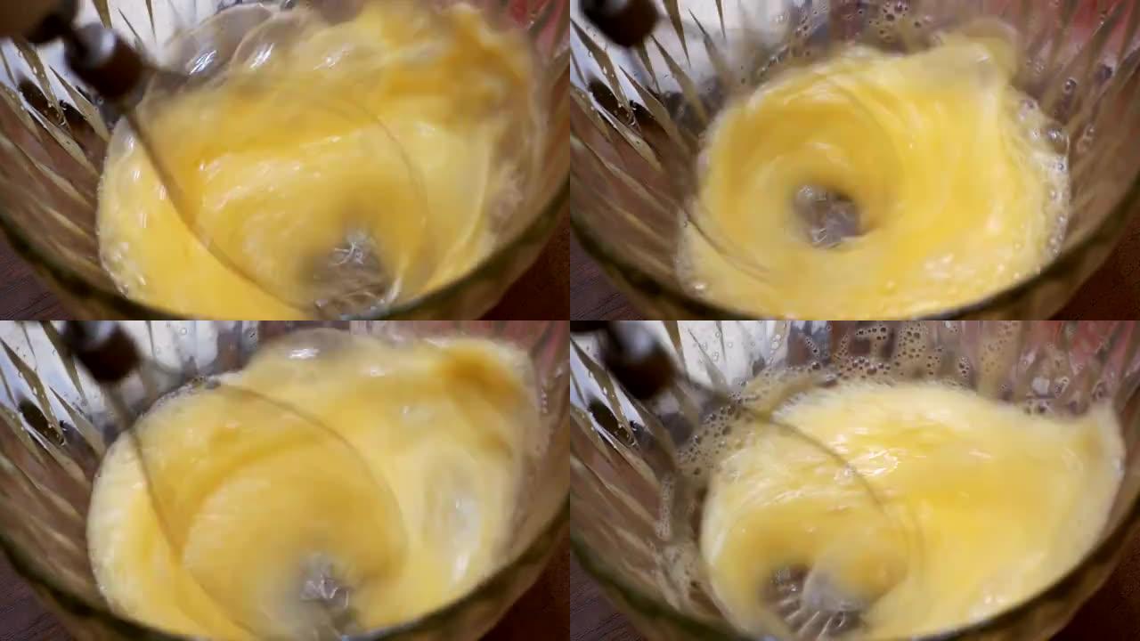 用电动手动搅拌器在透明碗中搅打鸡蛋