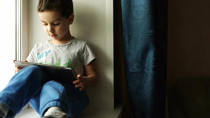 孩子坐在窗台上，使用平板电脑