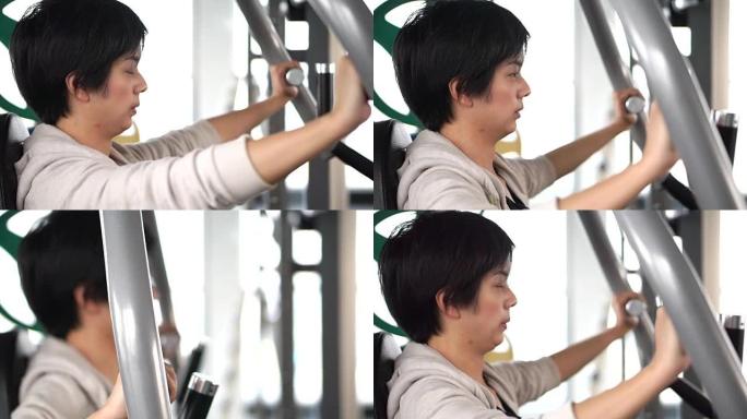 亚洲成年女运动员在健身馆锻炼做机器举重