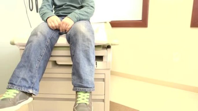 男孩紧张地坐在医生检查桌上