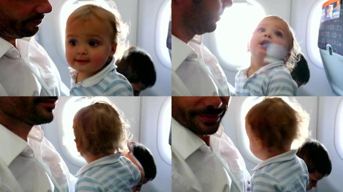父亲把婴儿抱在飞机上。等待飞机起飞的乘客。爸爸带着婴儿和孩子乘飞机旅行