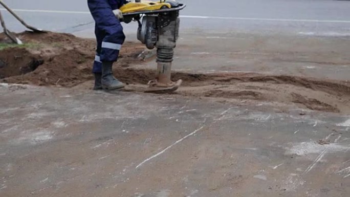 在街上使用建筑手提钻的工人。路上有自动钻撞沙的人。道路工程。施工，振动，特写