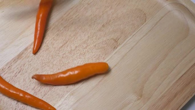 橙色辣椒扔在木板上