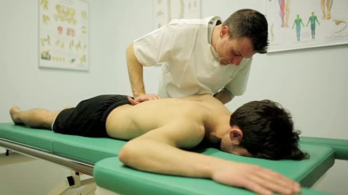 物理治疗师正在检查年轻患者的肩膀和背部疼痛