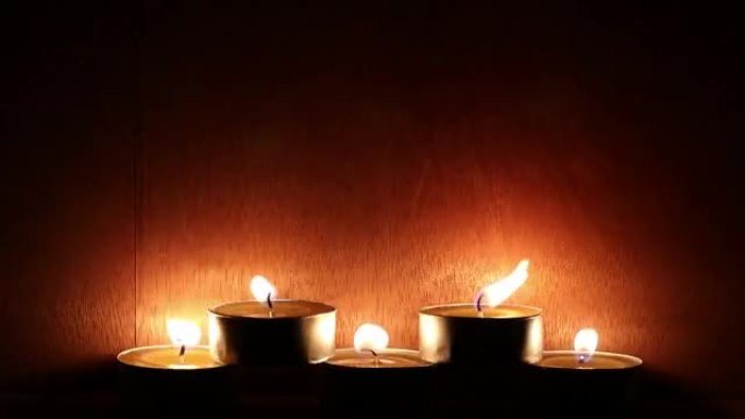 黑暗的房间里有一排木制墙壁的蜡烛。