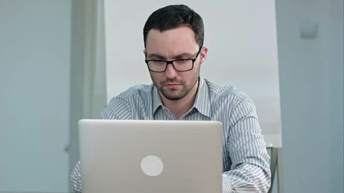 戴眼镜的帅气男老师在笔记本电脑上打字