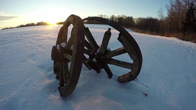 日落时雪中两个古老的木轮，时间流逝