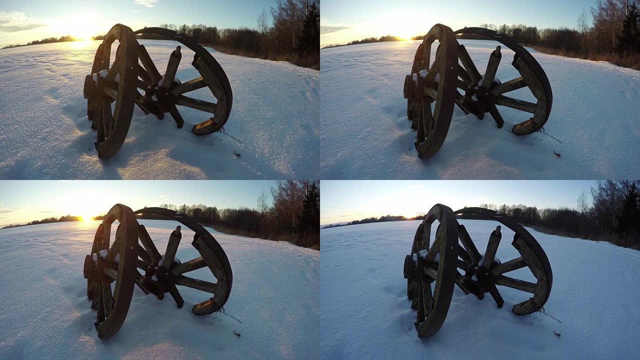 日落时雪中两个古老的木轮，时间流逝