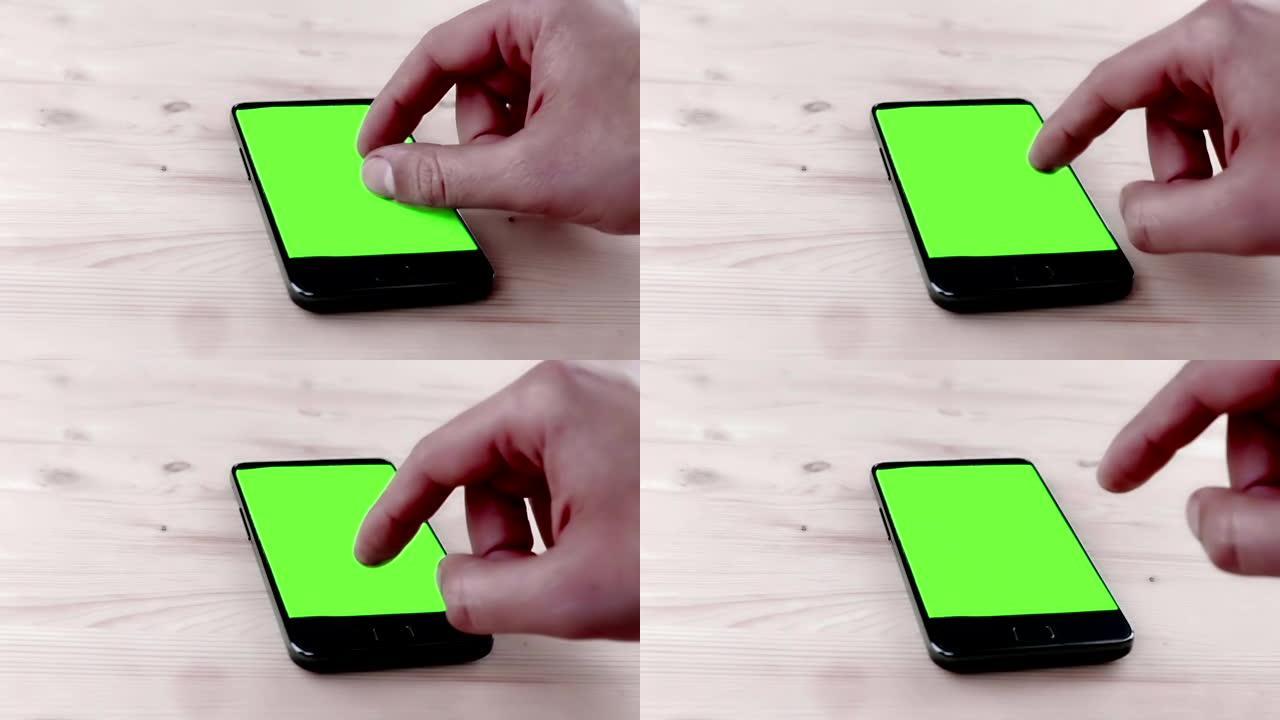 男人的手在办公室使用智能手机，色键，木桌上的绿色屏幕