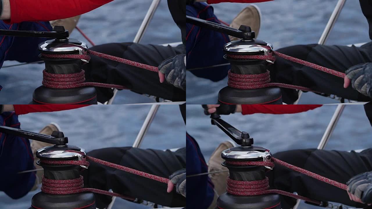 水手的手拉着游艇绞盘上的绳子。