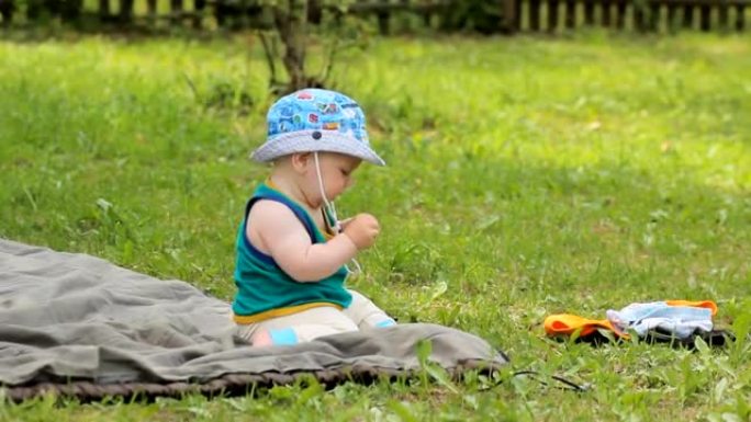 男婴坐在草地上，试图吃草
