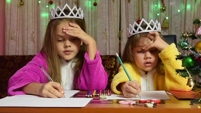 两个穿着睡袍的女孩坐在桌子旁给圣诞老人写信