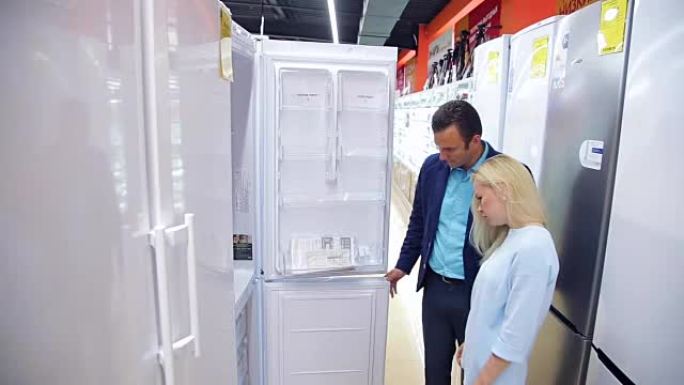 微笑的夫妇在商店里选择冰箱